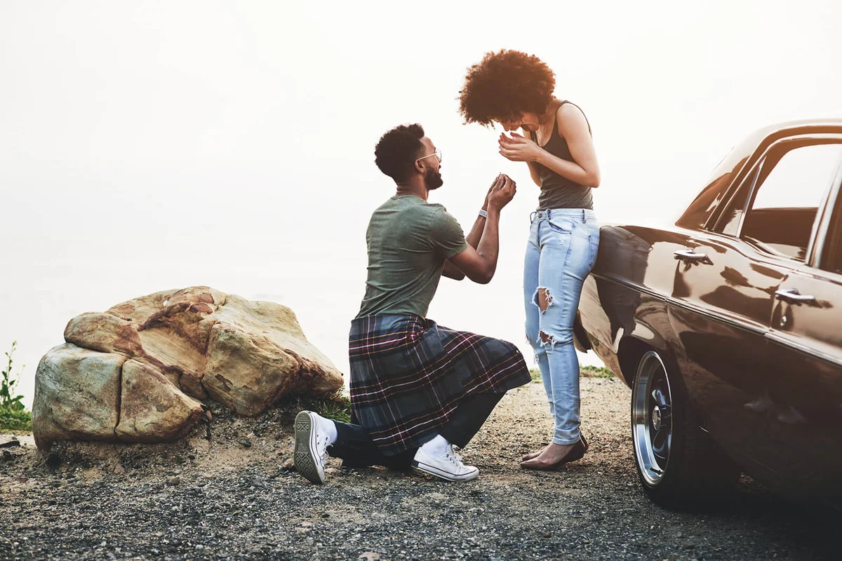 young man proposing to his girlfriend during a road trip