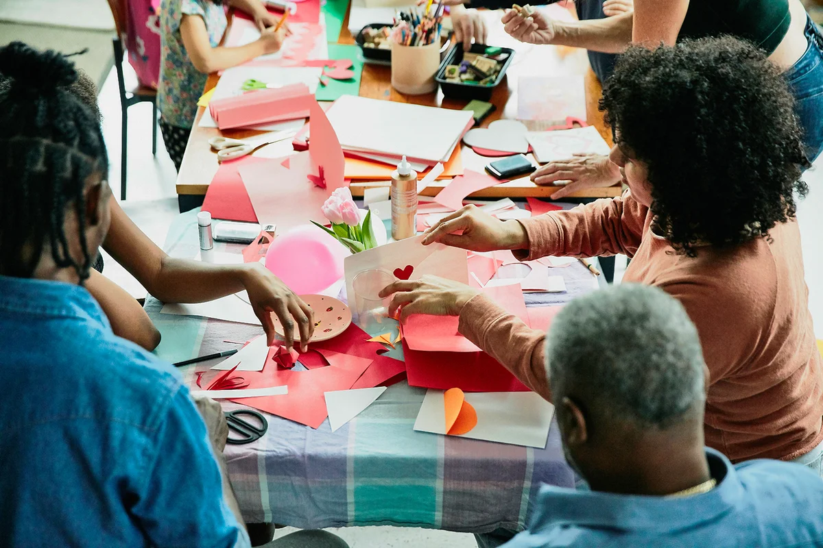 Family and friends gathered around table in home making crafts