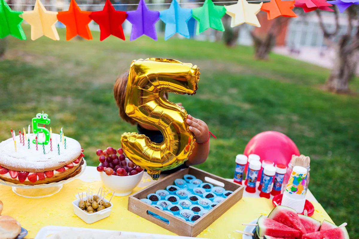 Little boy hiding behind golden balloon