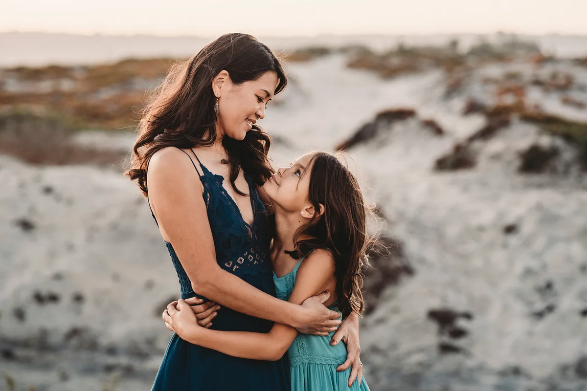 Happy mother hugging daughter at the beach