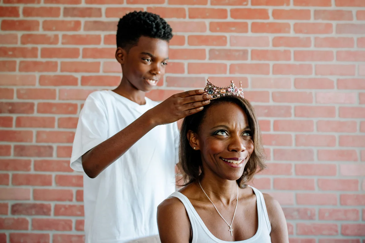 Son placing jewelled crown on seated mother