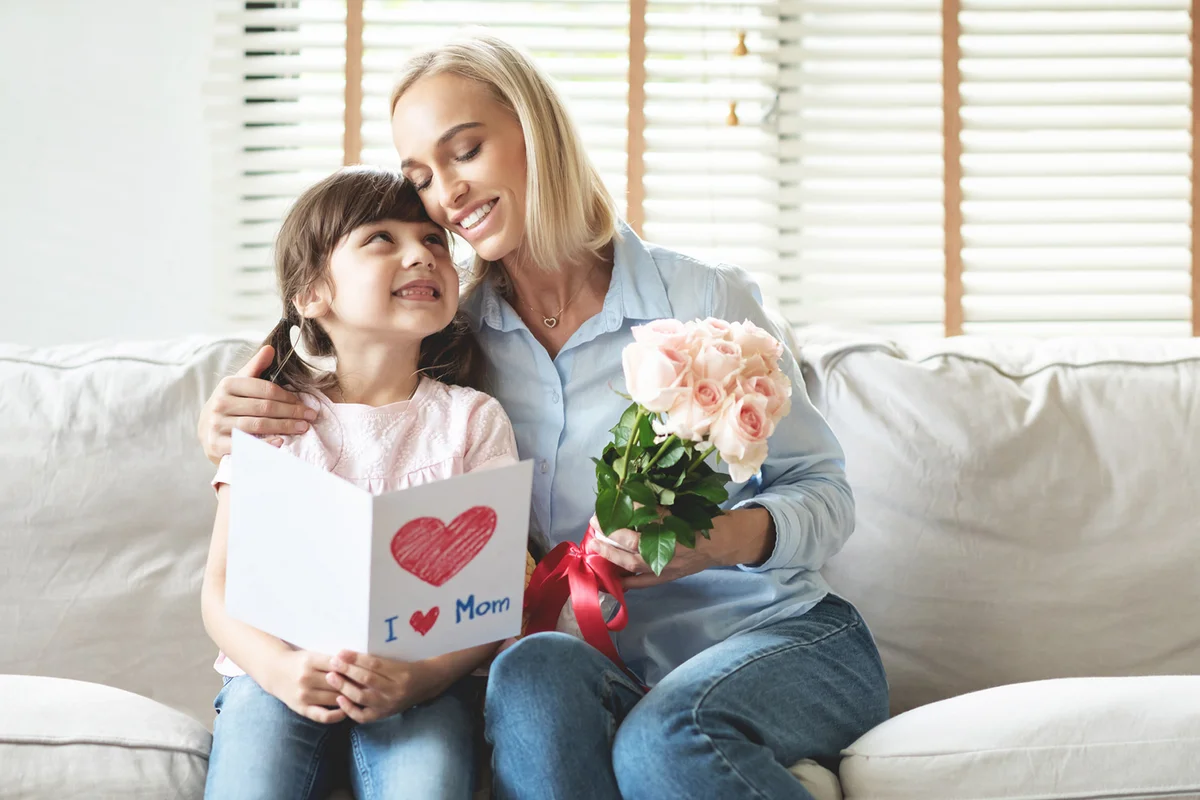 Mother And Daughter Holding Gifts While Sitting On Sofa