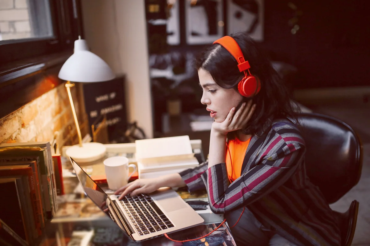 Young woman using laptop while listening to music