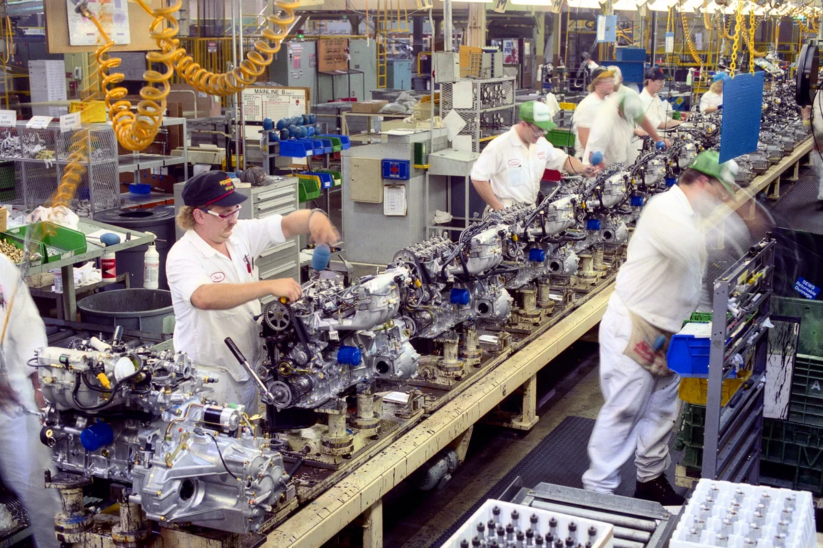 Factory workers building engines on assembly line