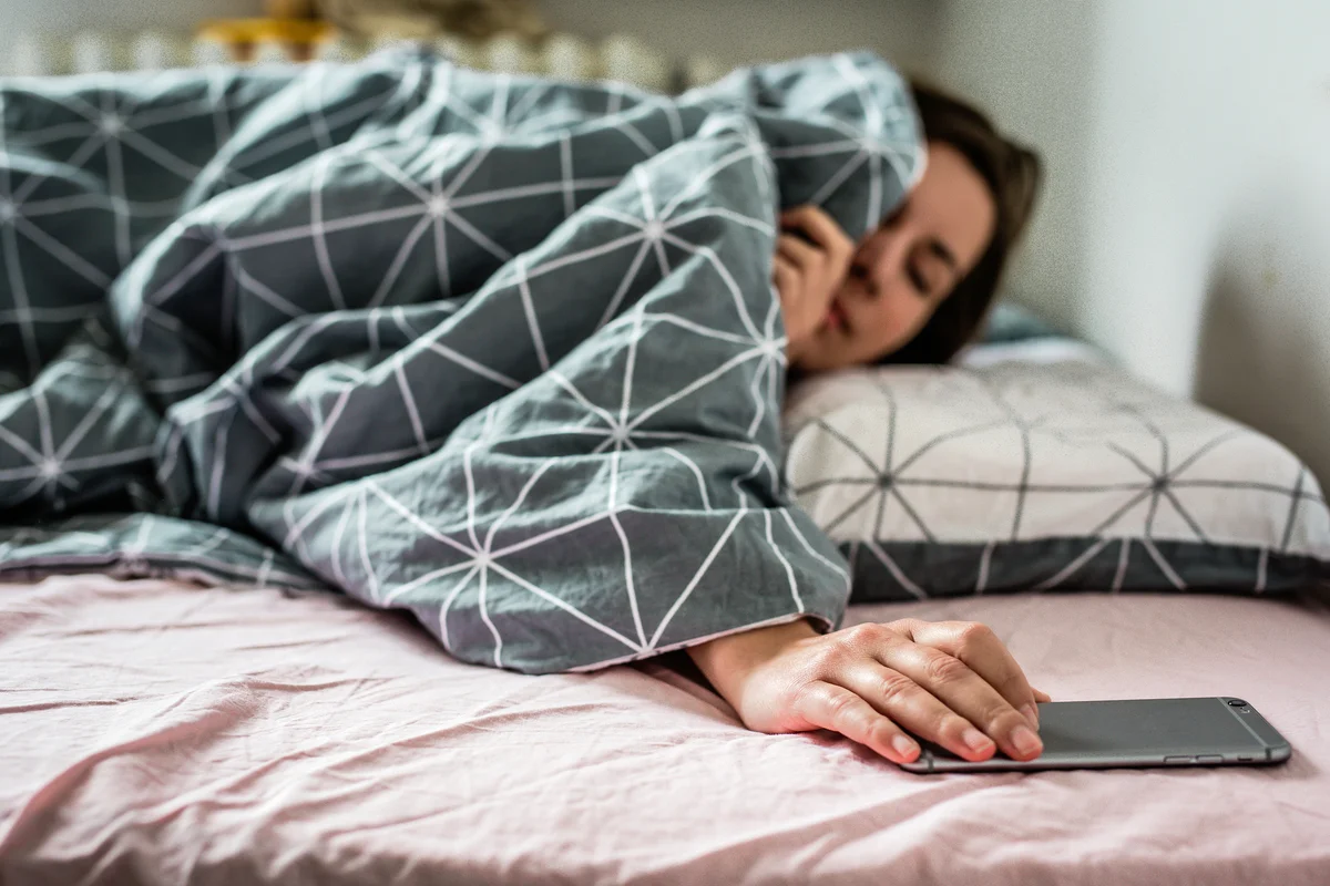 Woman in bed looking at smart phone