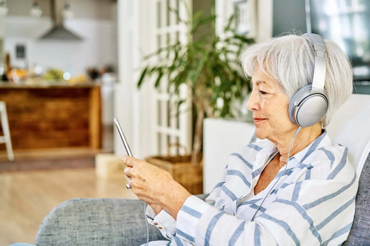 Senior woman wearing headphones with a smart phone