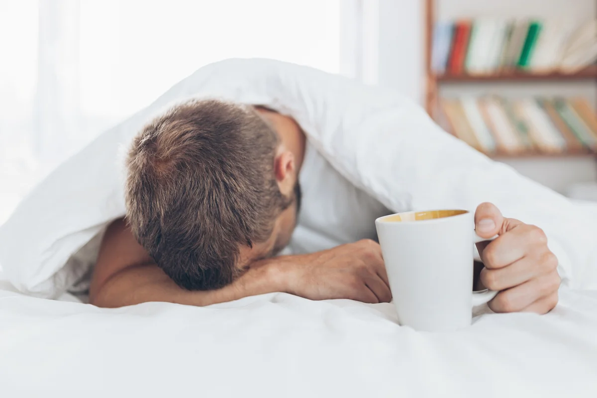 Man with hangover trying to wake up in the morning