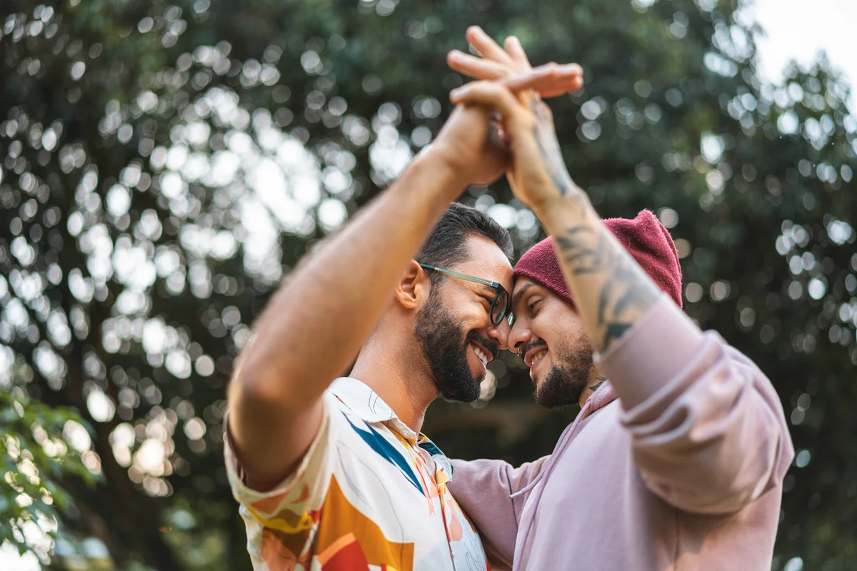 Gay couple touching hands in the public park
