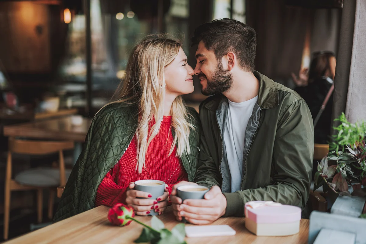 Beautiful young couple touching noses and smiling at cafe