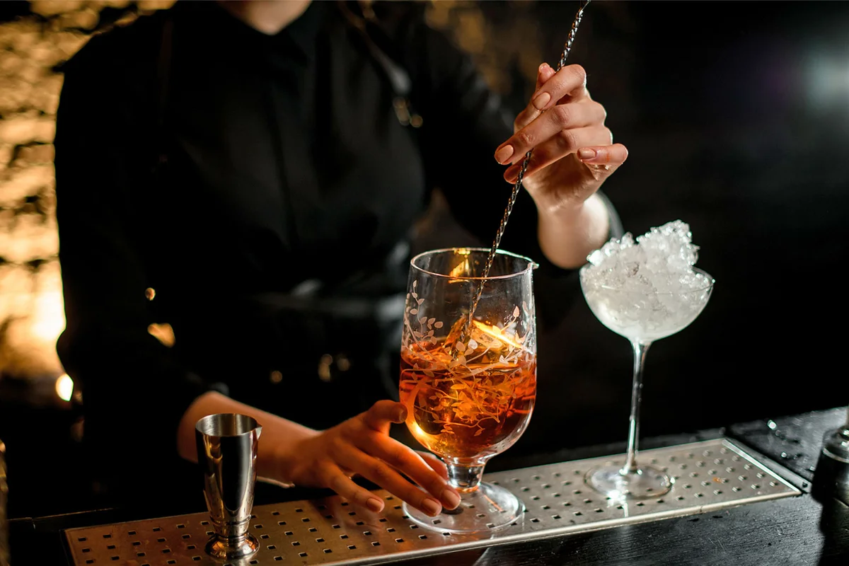 bartender mixing cocktail with long stir spoon