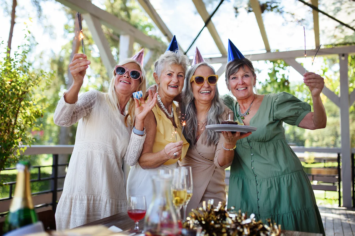 Senior women holding birthday cake during celebration outdoors