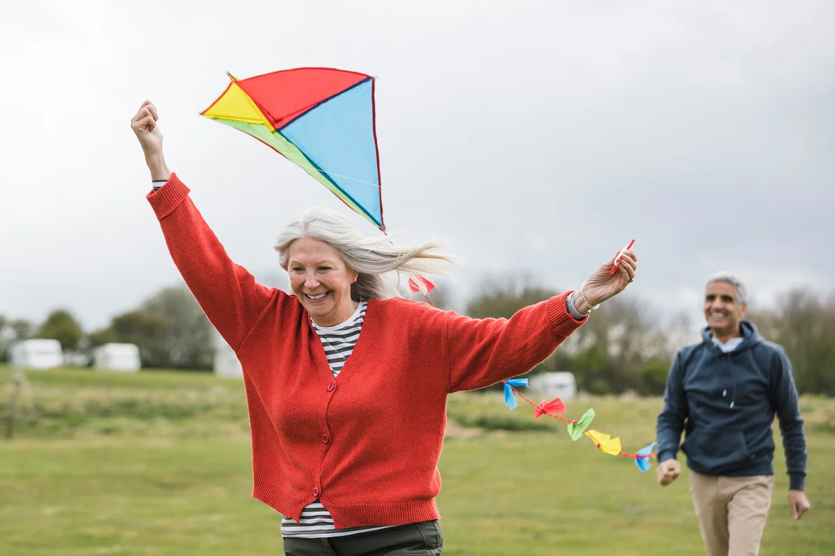 Senior friends flying a kite together in a field