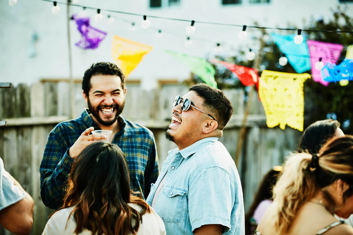 Laughing friends hanging out during backyard barbecue on summer evening