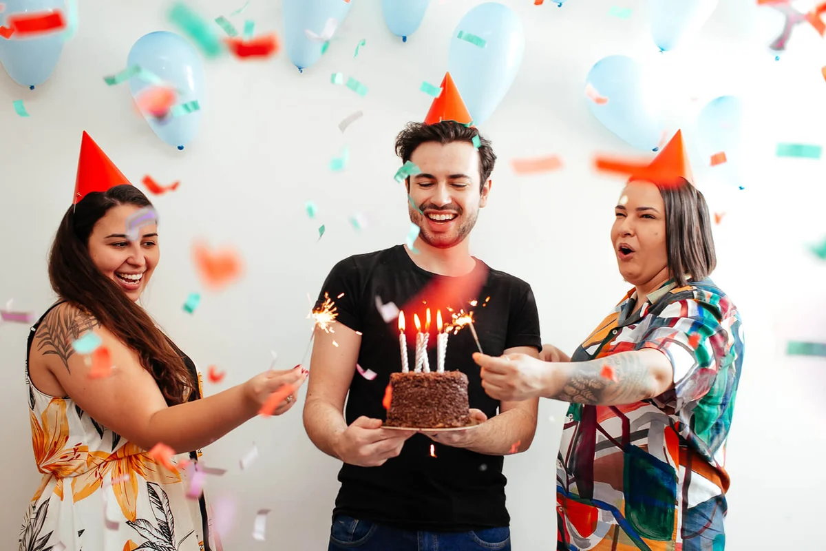 Young adult friends celebrating a birthday with cake and sparklers