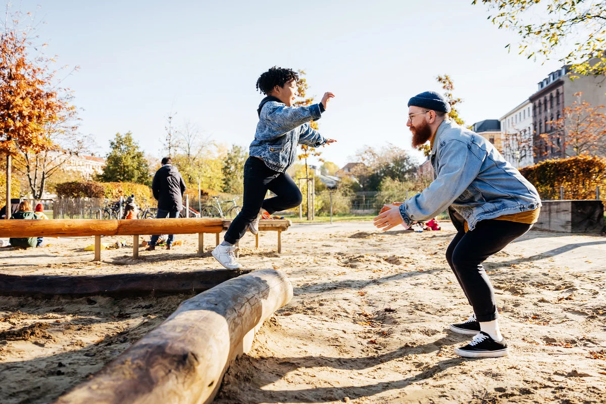 Young Boy Leaping Into Father Arms In Playground