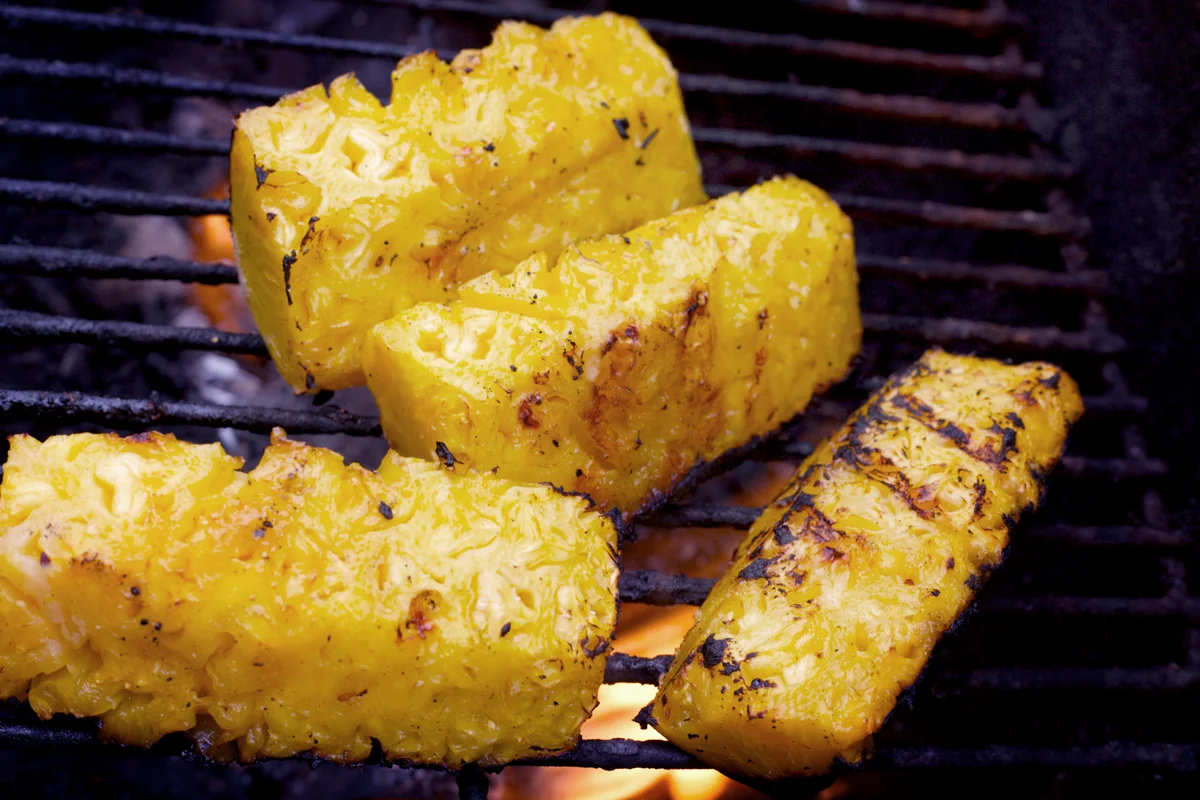 Grilled pineapple on grill with flames below