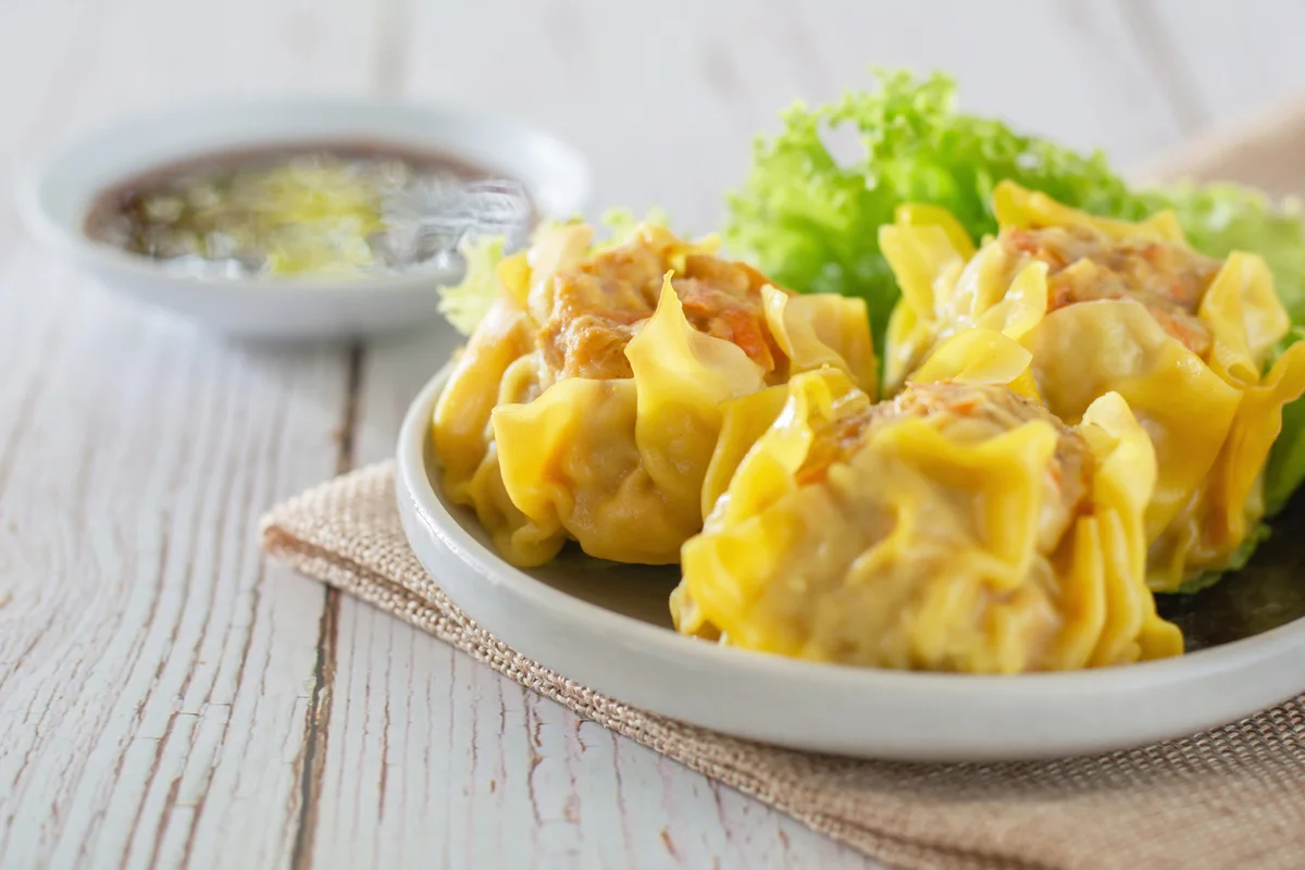 Chinese Steamed Dumpling, Shumai On White Dish Served With Soy Sauce And Lettuce Leaves