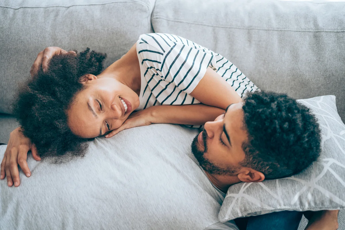 Young couple lying together on their sofa at home