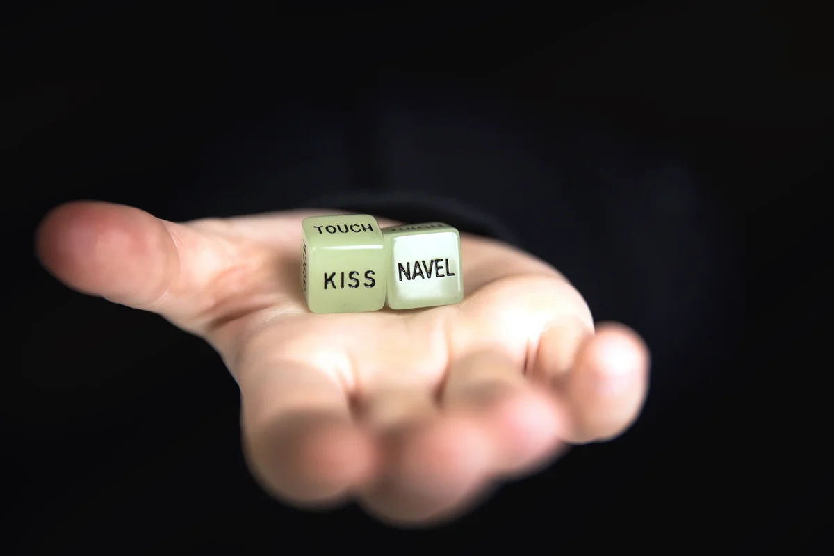 Hand holding two dice with erotic text for sexual game