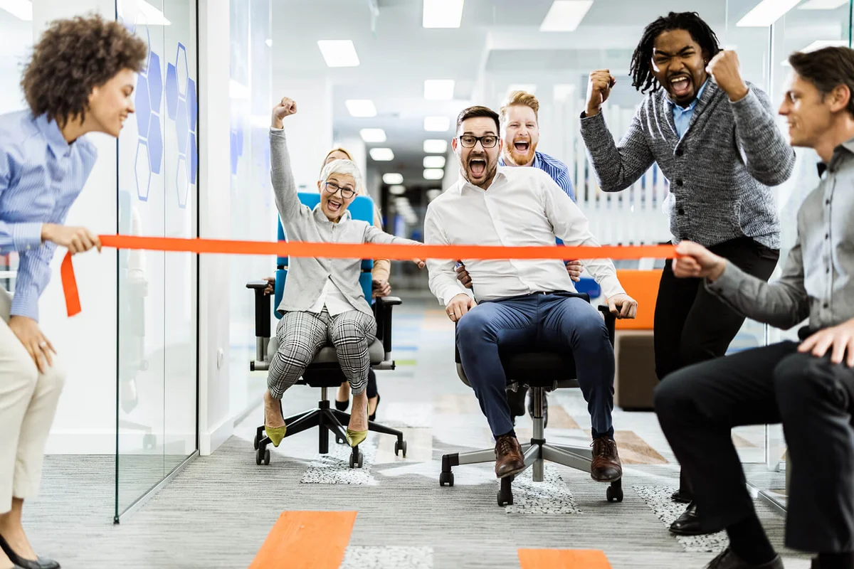 joyful colleagues having fun during chair race in the office