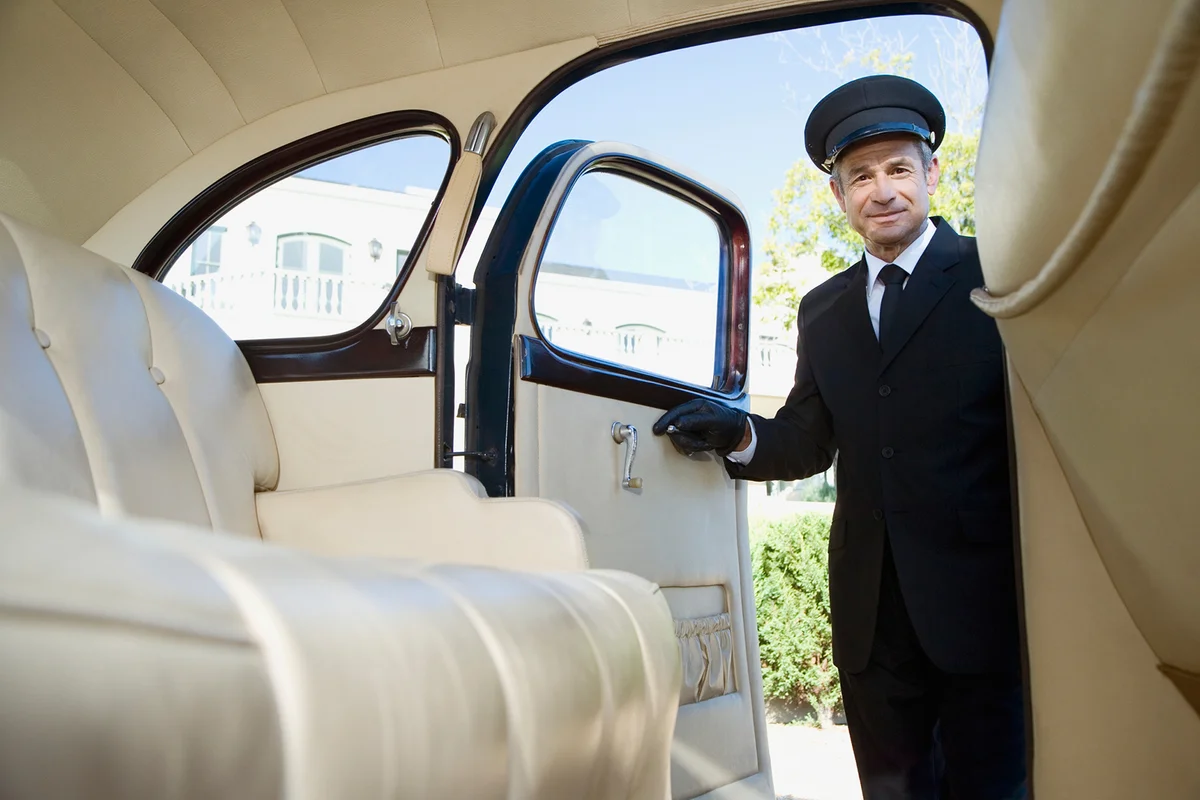 Chauffeur opening door of a vintage car