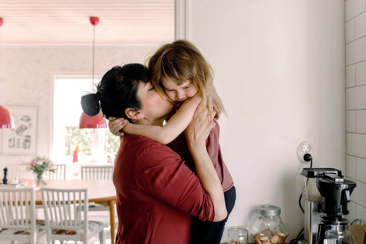 Mother kissing daughter at home