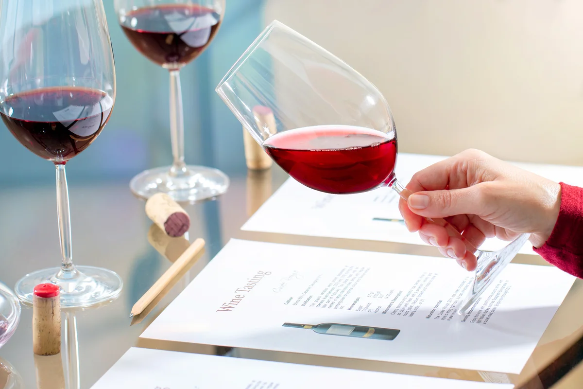 Enologist holding red wine glass at table