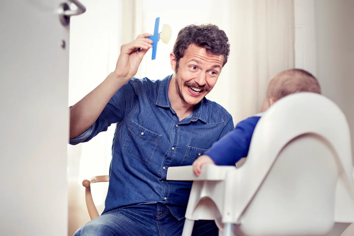 Father feeding baby in high chair