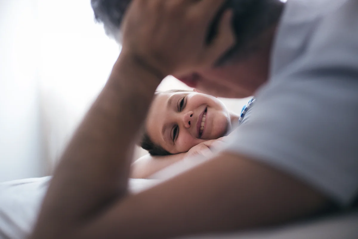 Father lying on the bed talking to his son