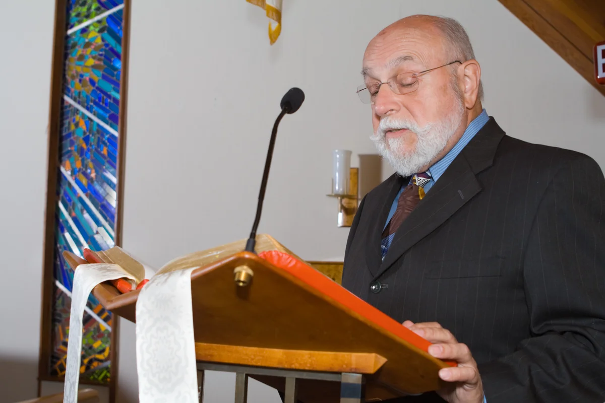 man reading at funeral at church podium