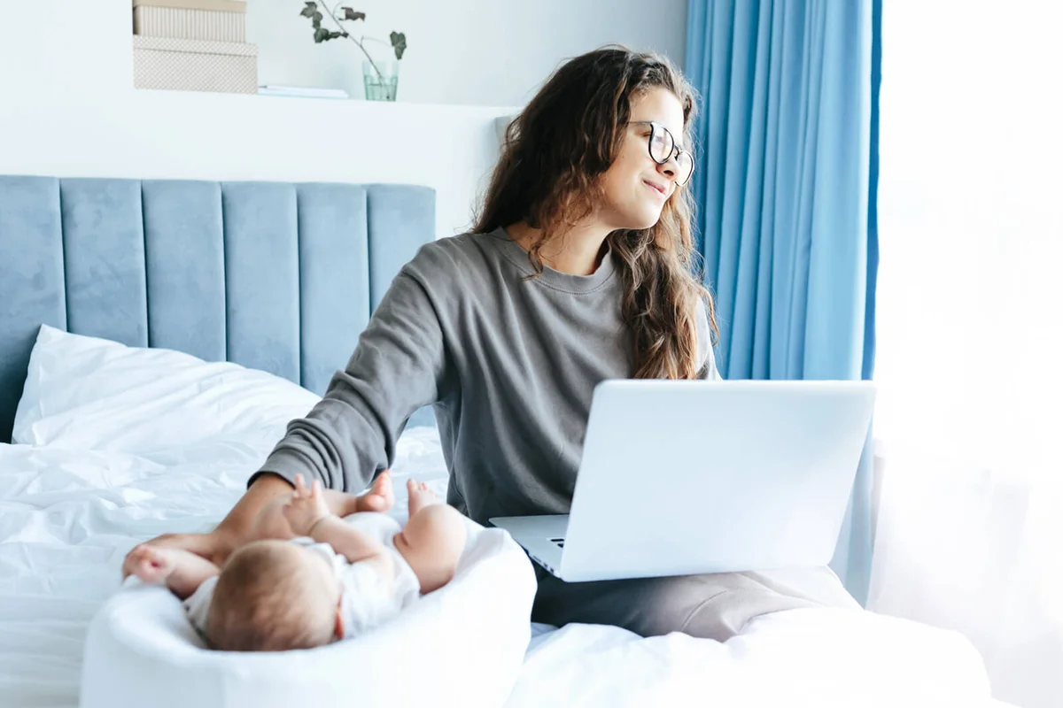 Mother at home with baby working on laptop