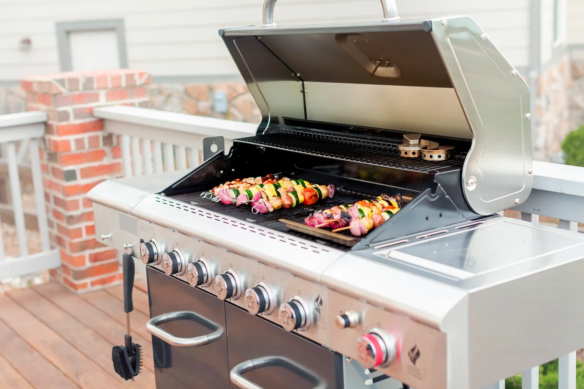 Grilling veggie skewers and chicken kebabs on outdoor gas grill