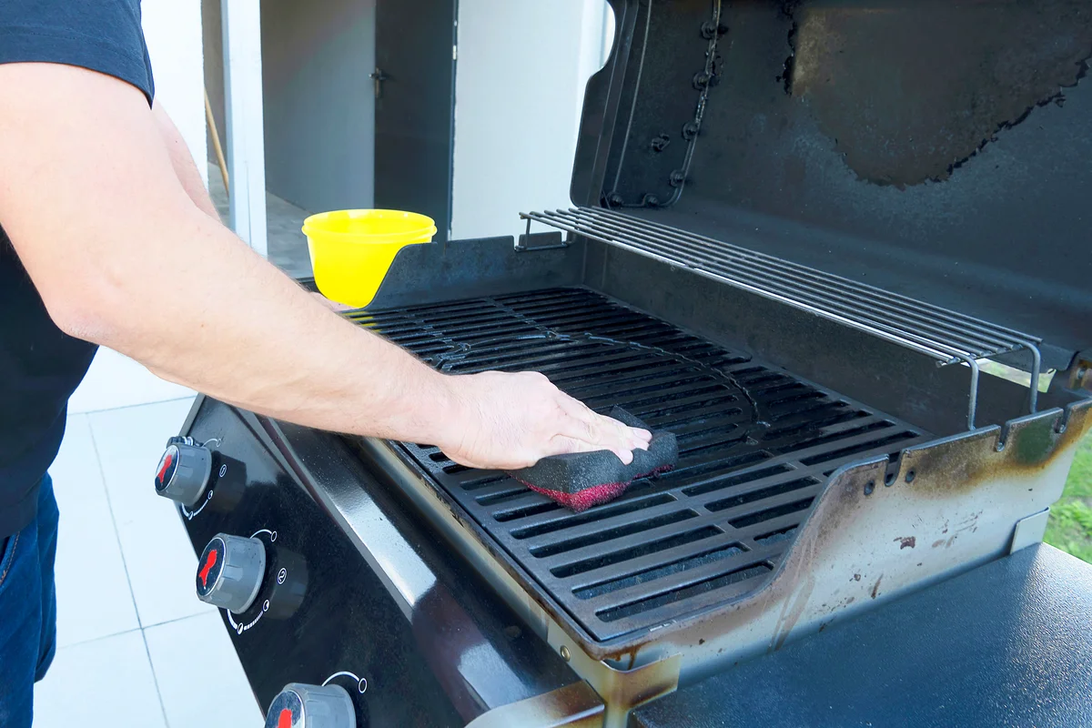 Hand cleans the black grill with a soft brush