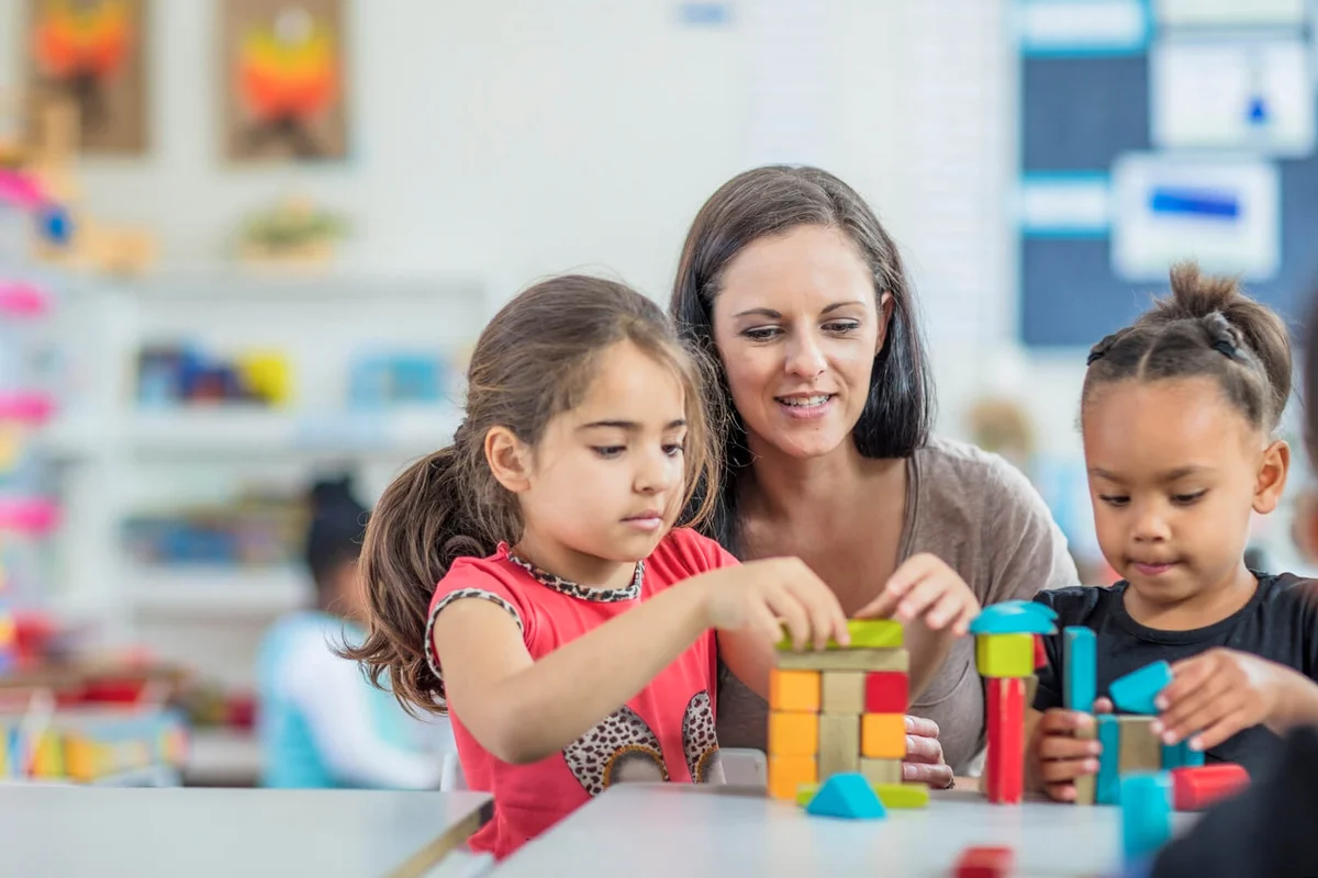Pre-school teacher playing with girls in kindergarten