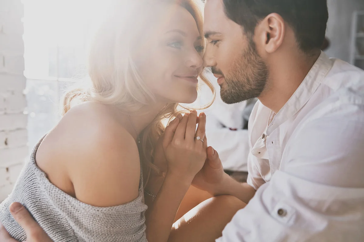 Beautiful young couple bonding and smiling while sitting in the bedroom