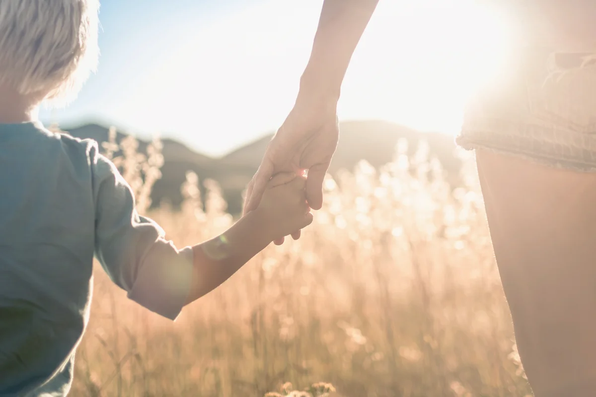 Mother and son holding hands walking at sunset