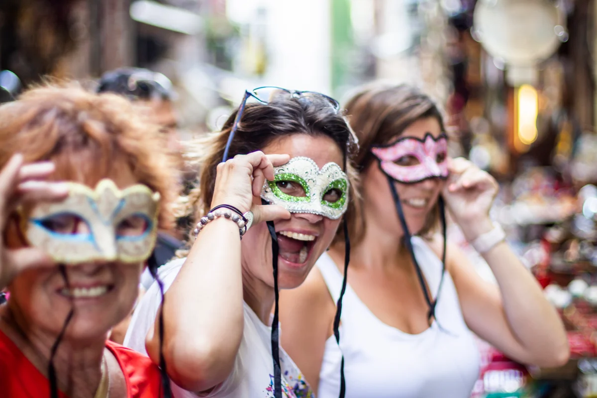 women on street with masks celebrating Mardi Gras