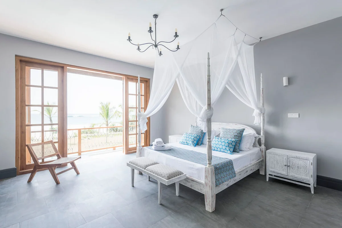 Four poster bed with mosquito net in bright hotel room