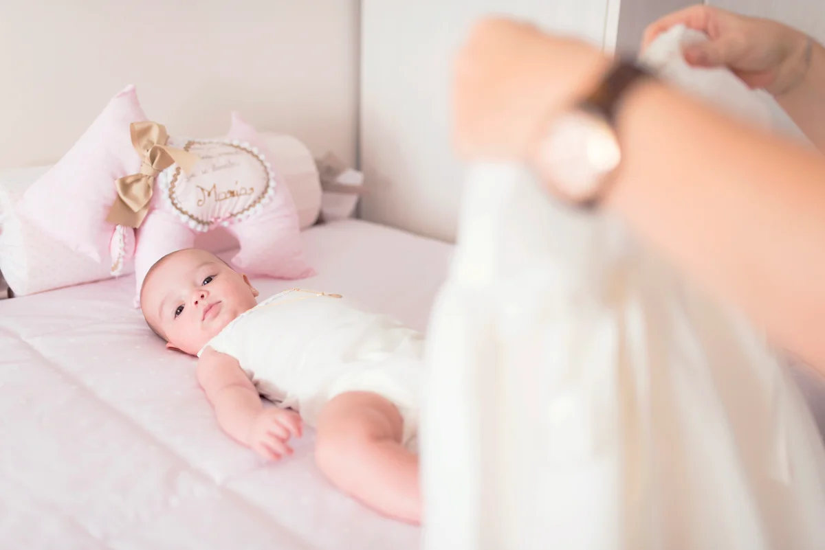 Mother clothing baby in home bedroom