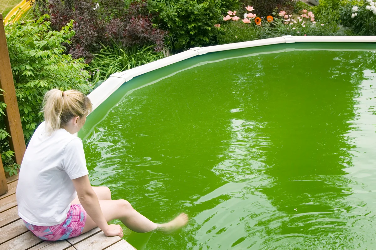 Girl sitting by the pool with disgustingly green water