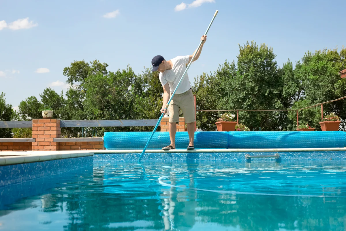 Man cleaning outdoor swimming pool