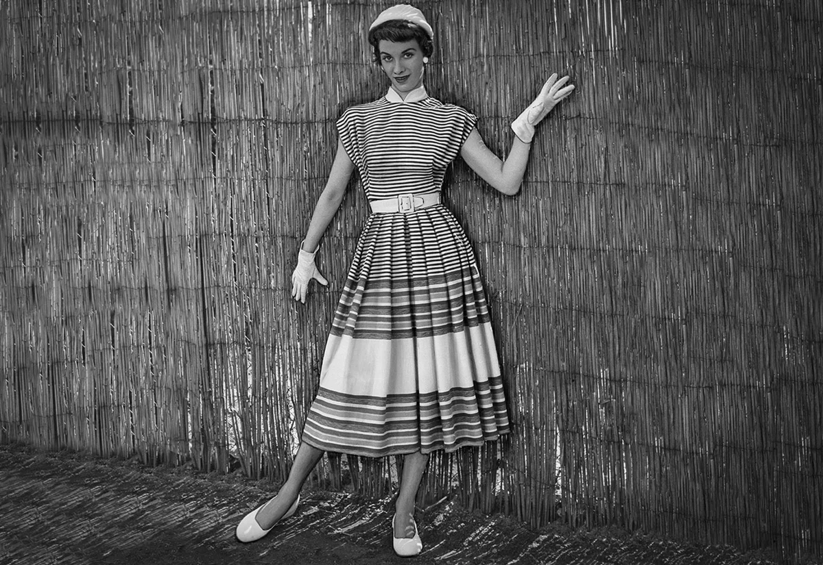 1950s fashion woman wearing summer striped dress with gloves and hat