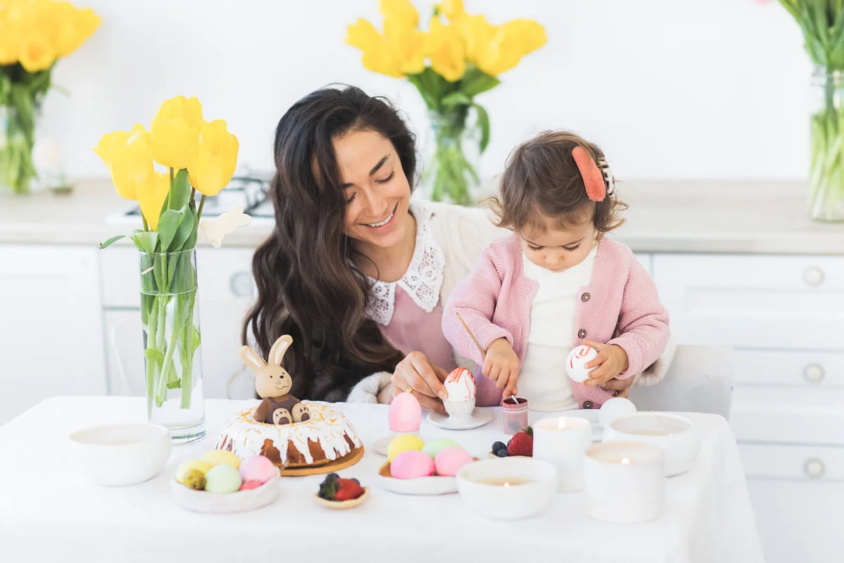 Beautiful mother with cute little daughter painting easter egg