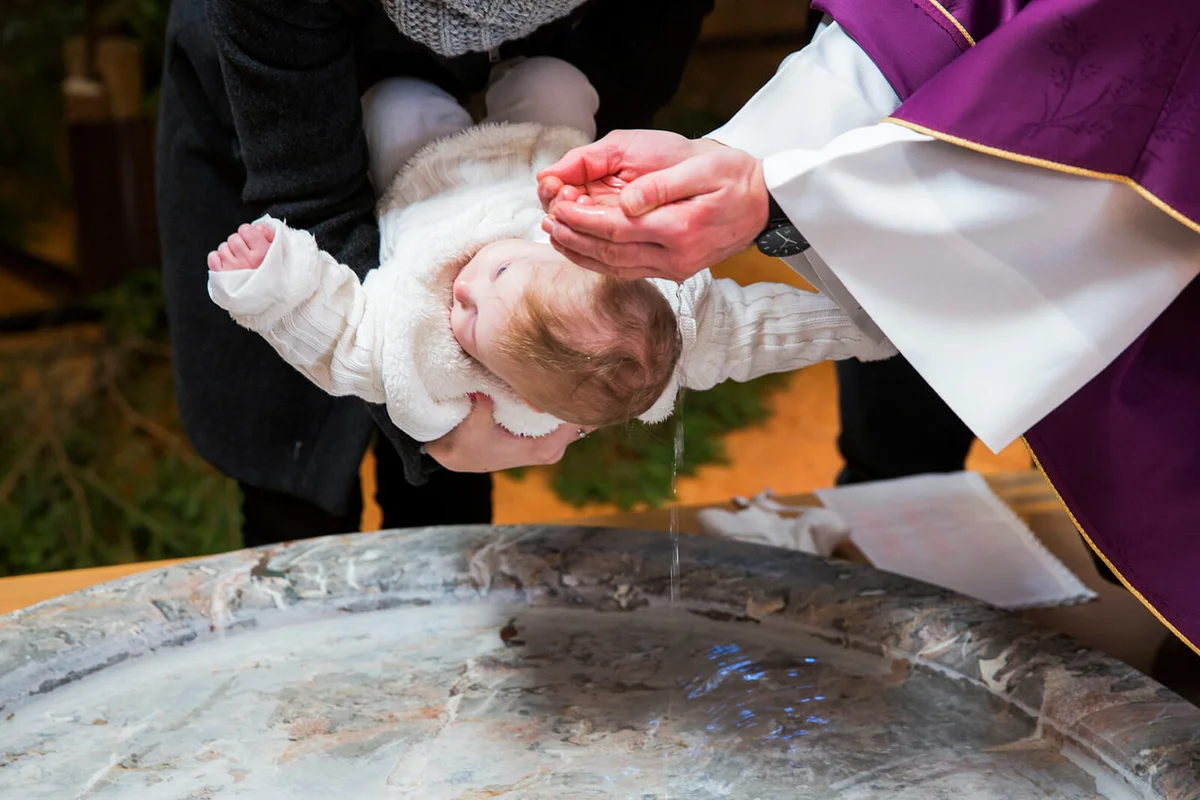 Priest is baptizing little baby girl in a church