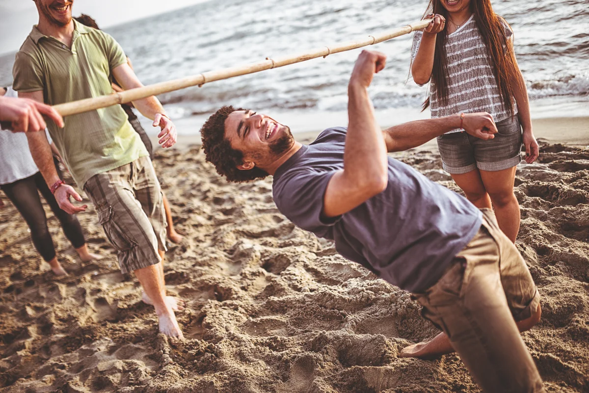 friend playing limbo dance at beach