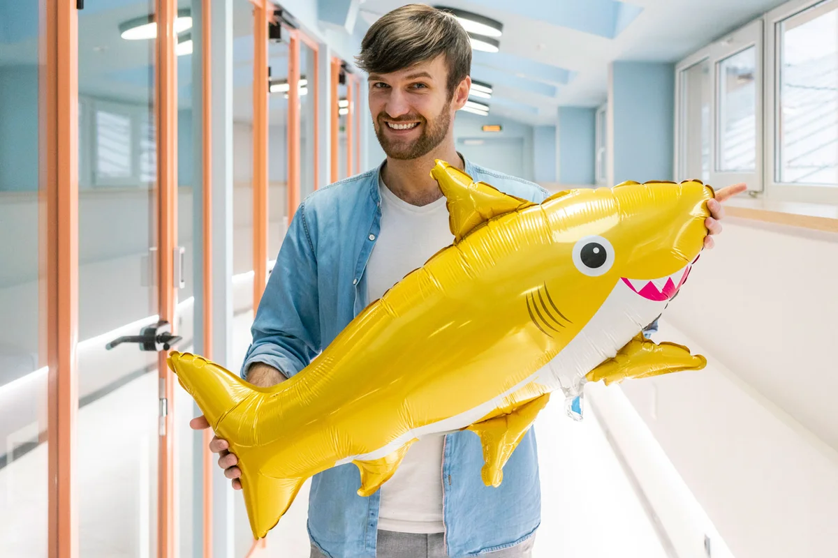man holding foil shark balloon
