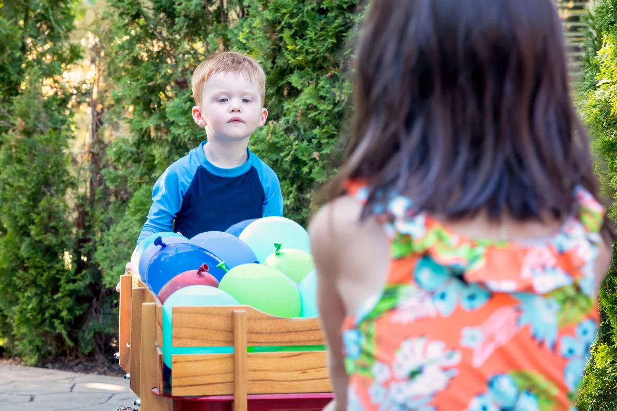 children with water balloons in wagon