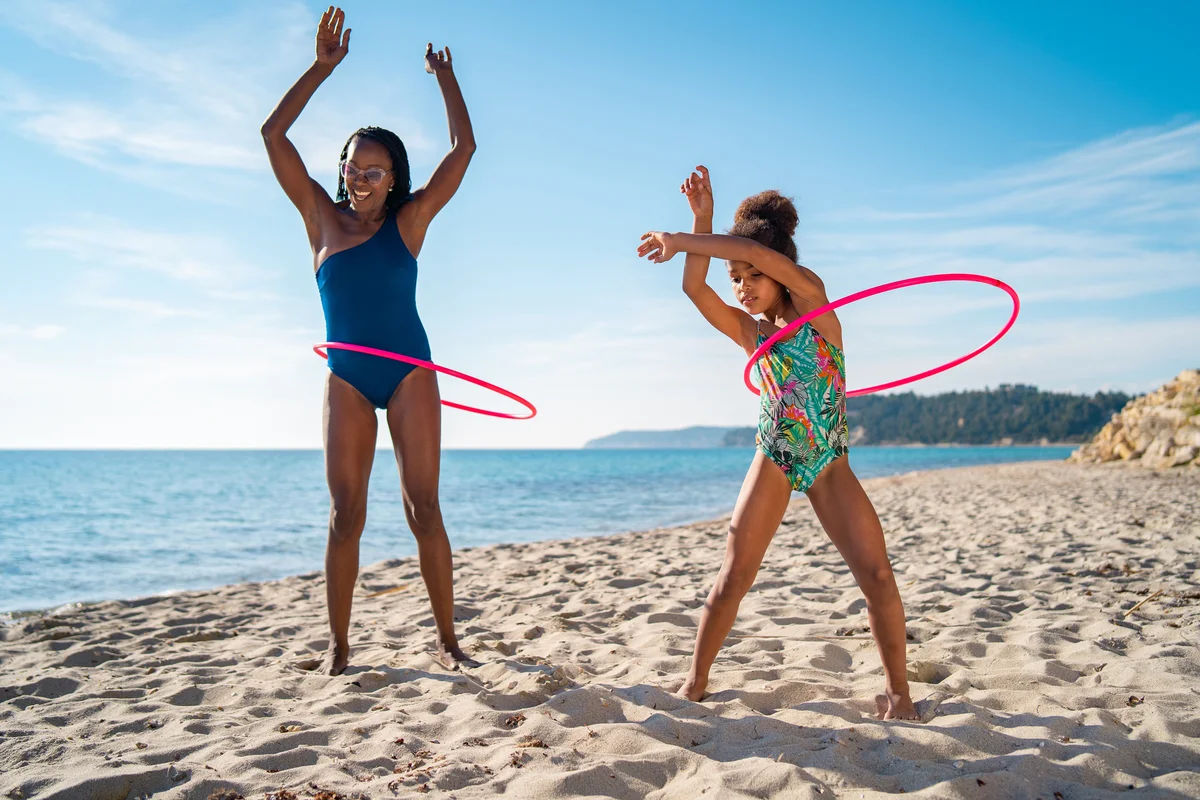 mother and daughter having hula hoop contest on beach