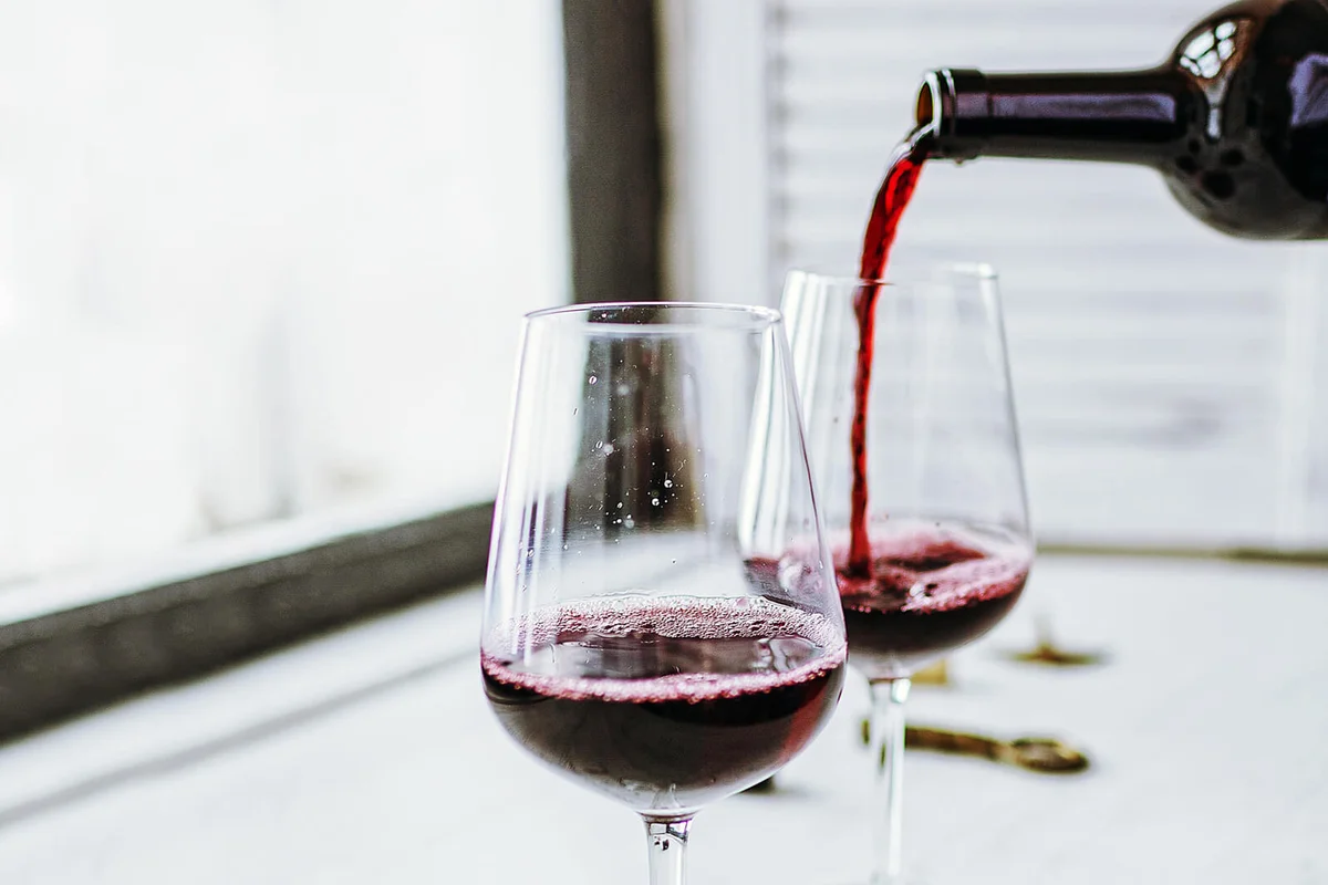 red wine pouring from bottle to wineglasses