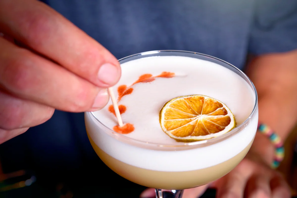 Barman finishes a Pisco Sour cocktail